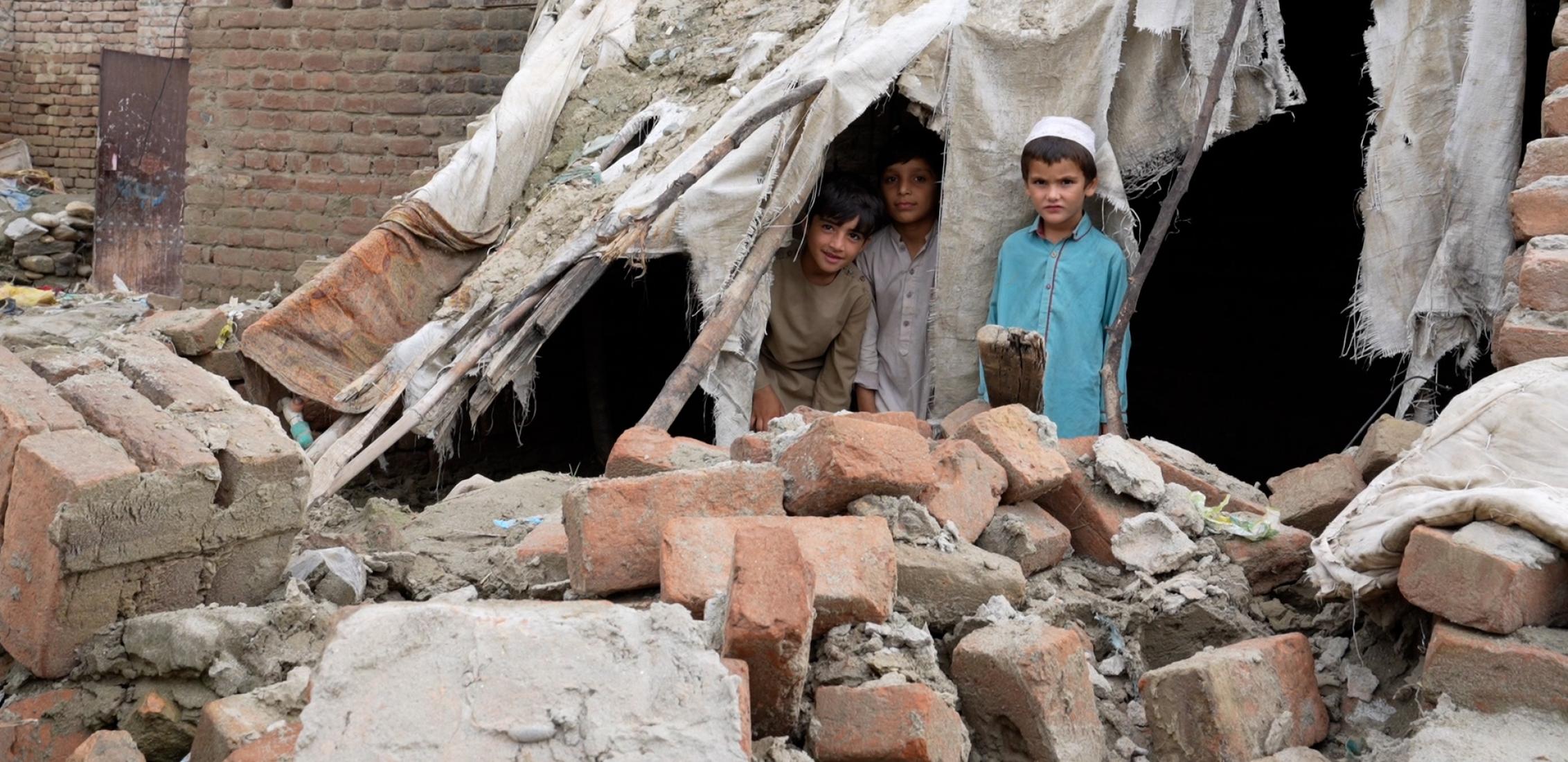 UN0693152/Fazel: El 22 de agosto de 2023, tres niños se acurrucaban bajo los escombros de su casa en Jalalabad, destruida por las recientes inundaciones en la provincia de Nangarhar, al este de Afganistán.